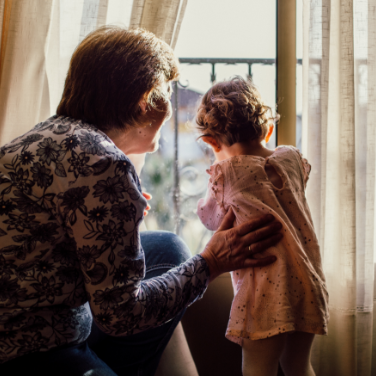 grandmother with baby looking out curtains